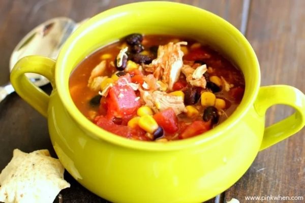 A flavorful Mexican chicken soup served in a vibrant green bowl.