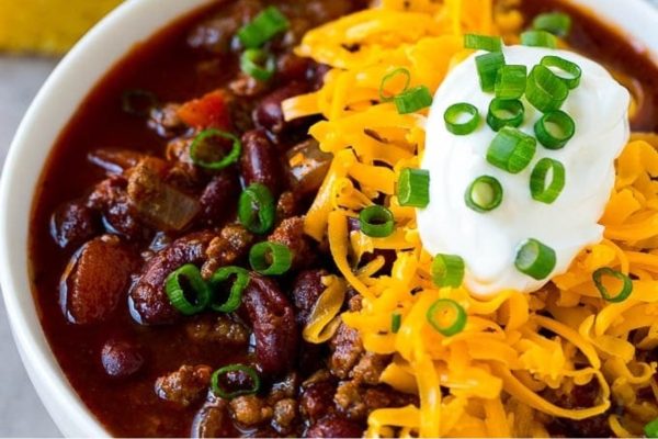 A bowl of chili with cheese and sour cream.