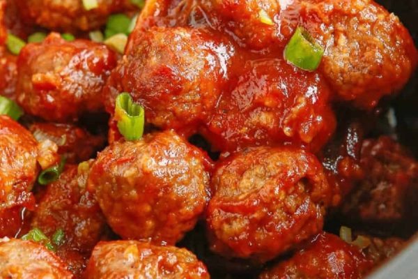 A bowl of meatballs with sauce and green onions.