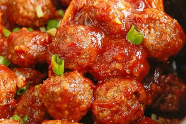 A bowl of meatballs with sauce and green onions.
