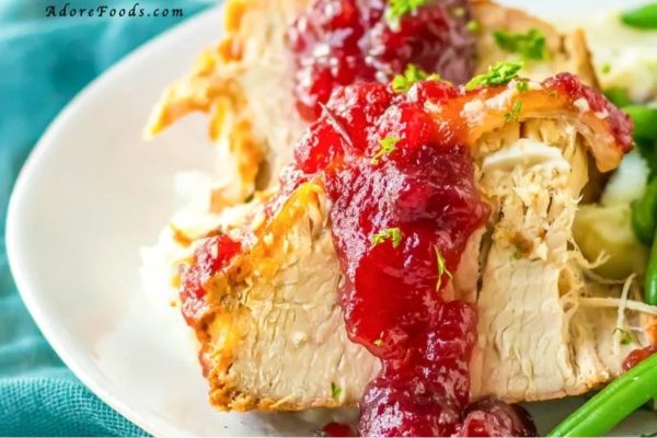 Turkey with cranberry sauce and green beans on a plate.
