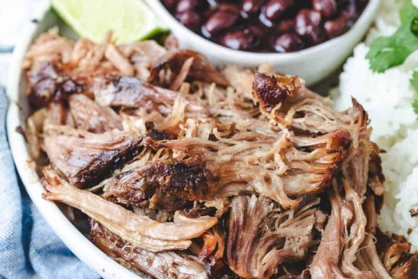 Pulled pork on a plate with rice and beans.