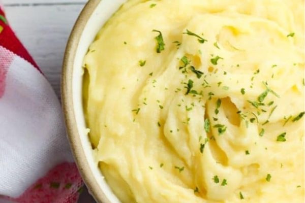 A bowl of mashed potatoes with parsley.