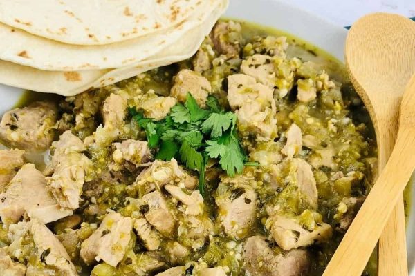 Chicken enchilada in a white bowl with tortillas.