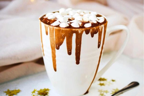 A cup of hot chocolate with marshmallows and sprinkles.