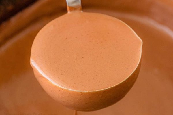 A spoon is being held over a bowl of chocolate.