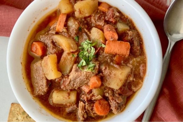 A bowl of beef stew with carrots and potatoes.