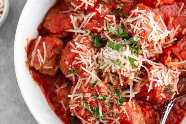 Meatballs in tomato sauce in a white bowl.