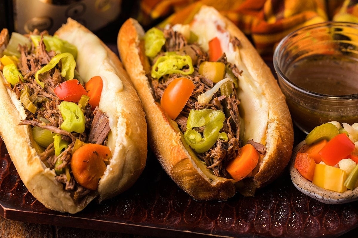 Two sandwiches with meat and vegetables on a tray.