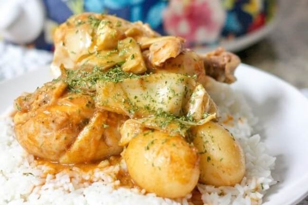 A white plate with rice and chicken on it.