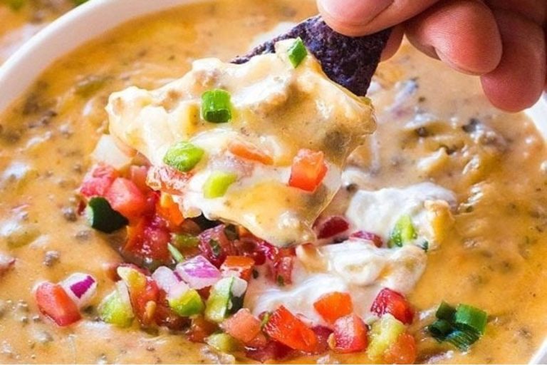 A person enjoying a slow cooker cheese dip with a tortilla chip.