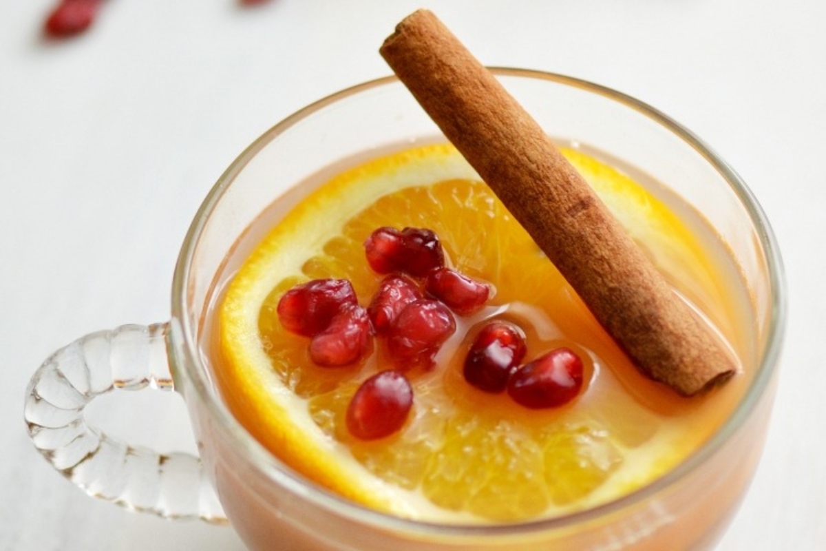 A cup of hot mulled wine with cinnamon sticks and orange slices.