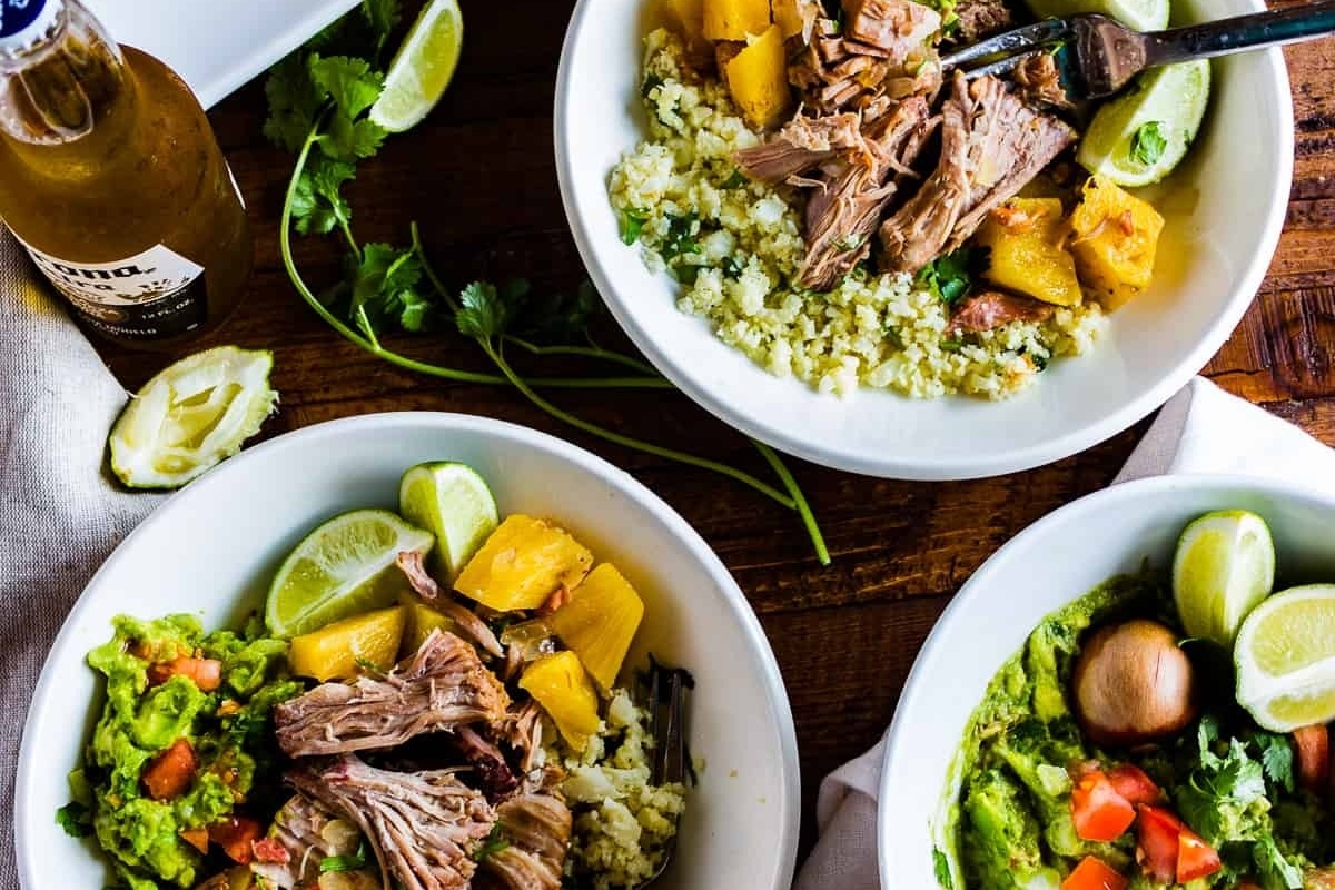Three bowls of pulled pork with guacamole and guacamole on a wooden table at a Dinner Party.