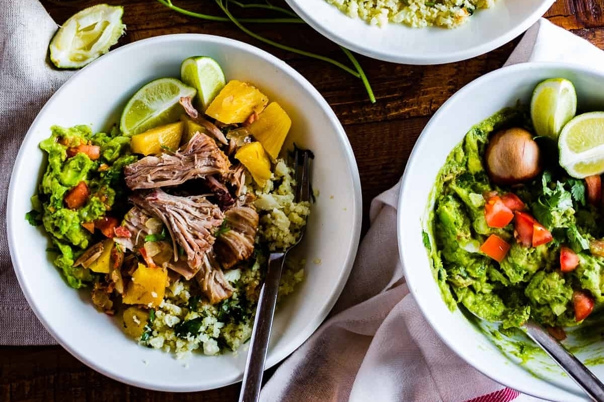 Three bowls of slow cooker recipes - meat, rice and guacamole on a wooden table.