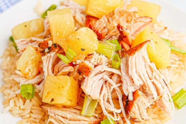 A plate of rice with chicken and pineapples on it.