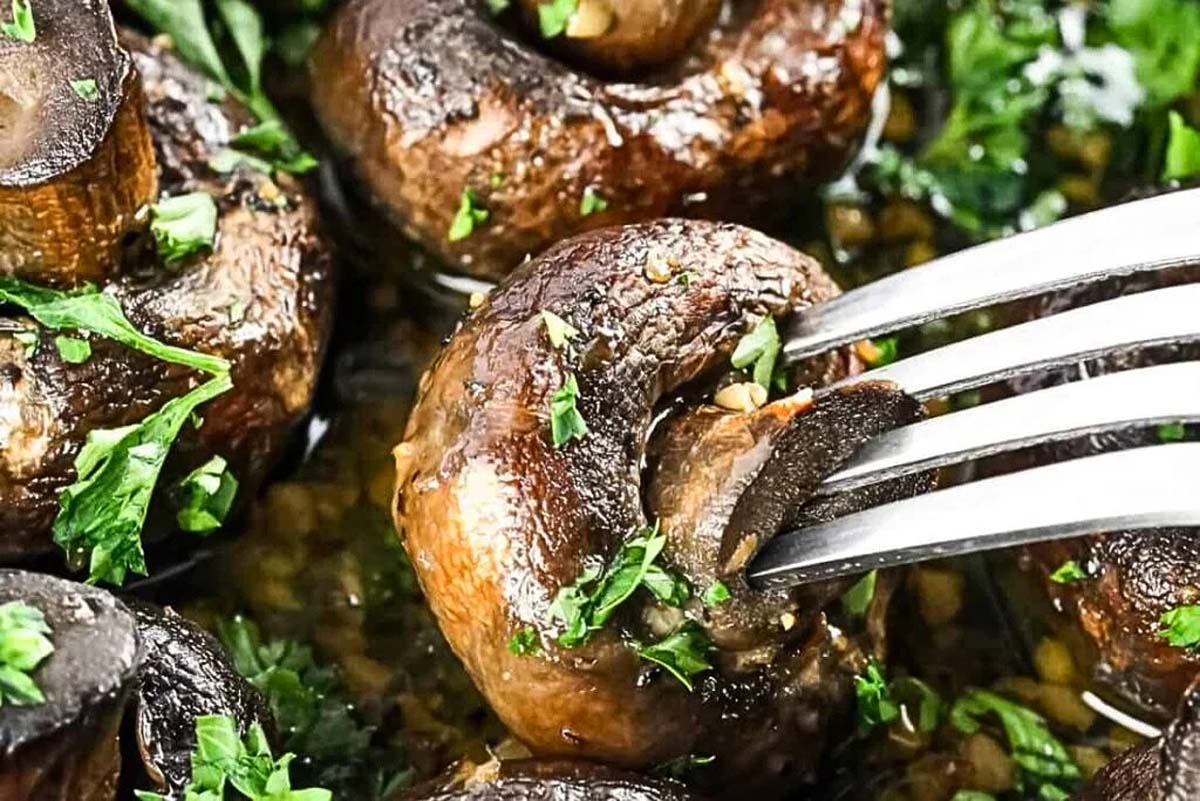 A fork is being used to eat some mushrooms for a delicious meal.