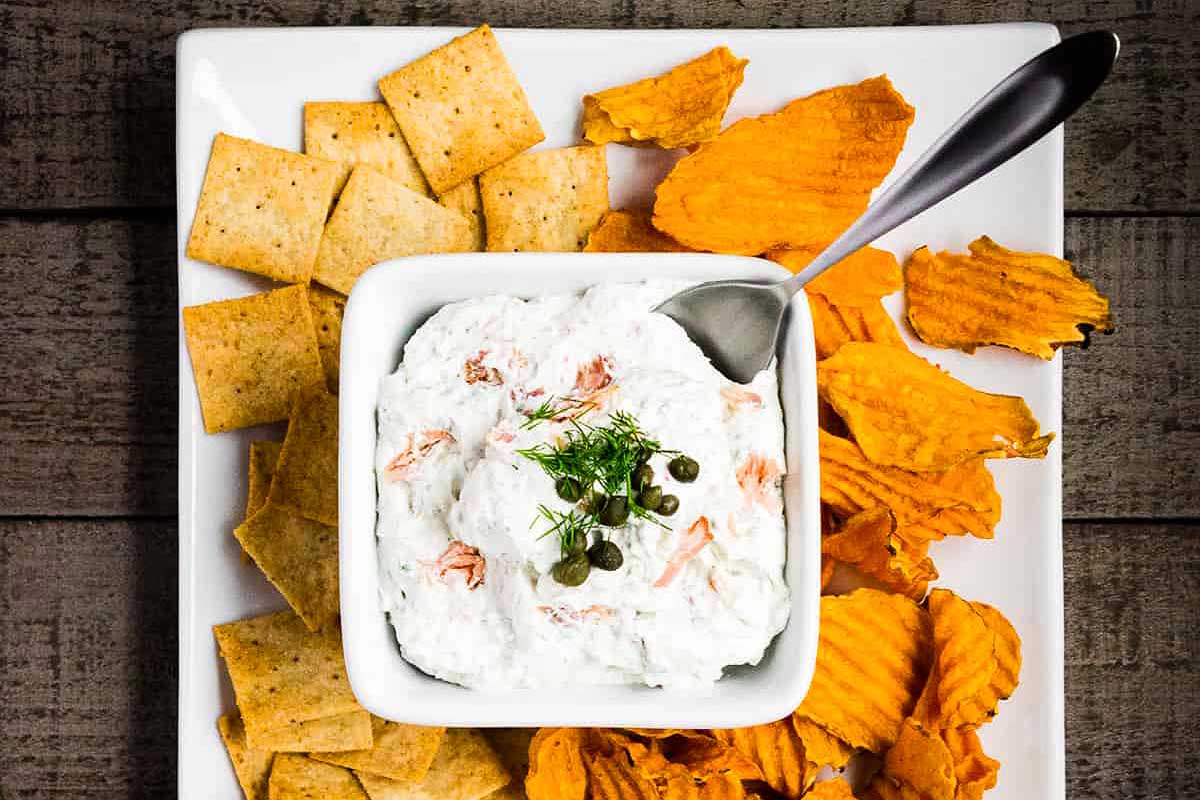 Salmon dip with crackers on a white plate.