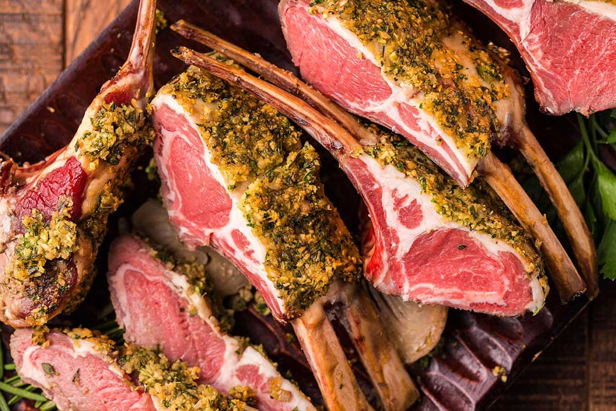 Roasted lamb chops on a plate with herbs.