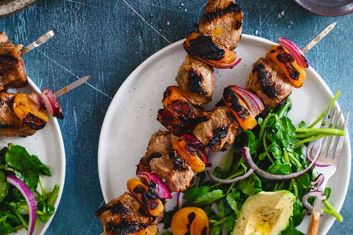 Grilled meat skewers with arugula and oranges are a flavorful and refreshing dish.