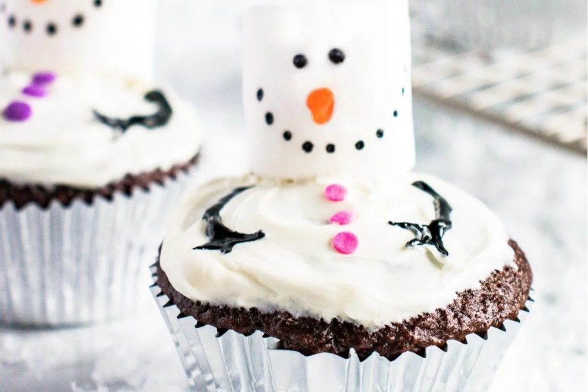 Cute Christmas cupcakes with icing and marshmallows in the shape of snowmen.
