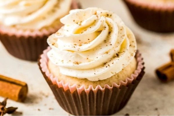 Christmas cupcakes with whipped cream and cinnamon sticks.