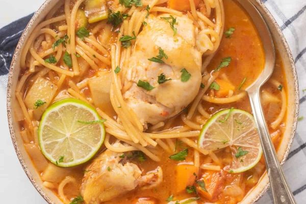 A delightful recipe for chicken noodle soup with a zesty twist of lime and lime wedges.