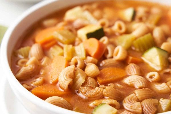 A bowl of vegetable soup with noodles and vegetables.