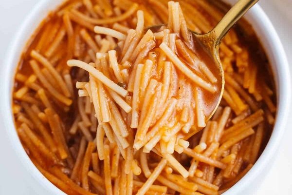 A spoonful of spaghetti in a white bowl.