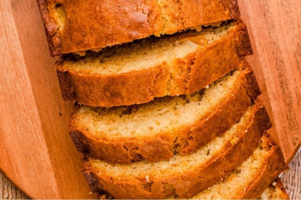 A slice of banana bread on a wooden cutting board.