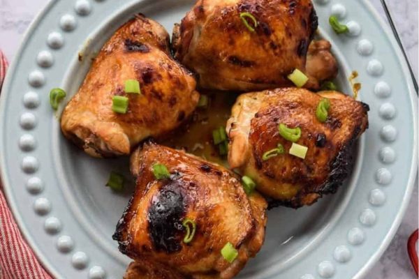 Pieces of soy glazed chicken thighs served on a plate.