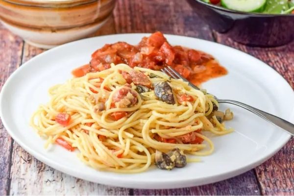 A plate of spaghetti with tomato sauce and vegetables.