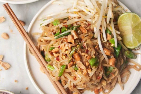 Budget-friendly Thai noodles on a white plate with chopsticks.