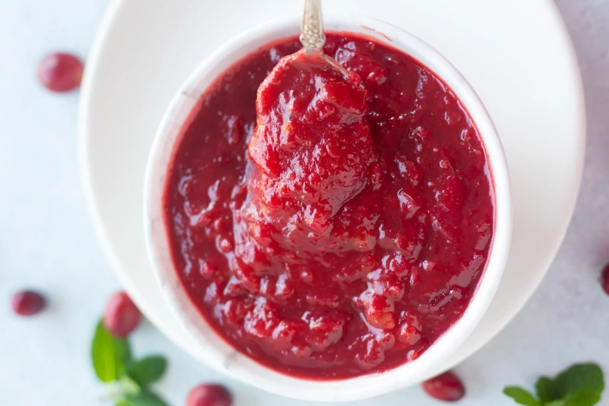 Delicious Cranberry sauce in a white bowl with a spoon, perfect for your Thanksgiving recipes.