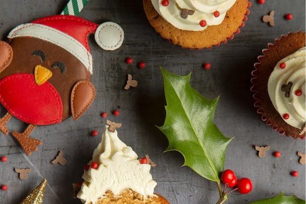 Christmas cupcakes decorated with holly leaves and santa hats.