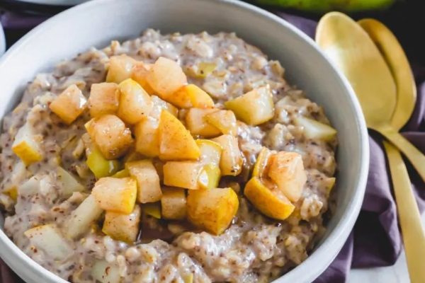A bowl of oatmeal with apples and cinnamon.