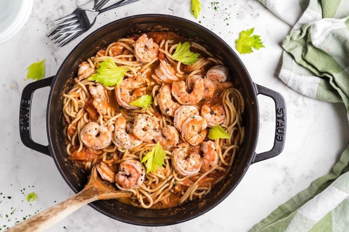 Pasta with shrimp in a skillet on a marble tabletop.