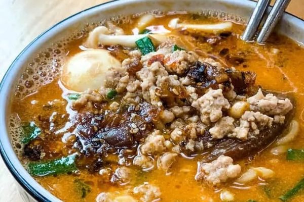 A bowl of ramen soup with meat and noodles in it.