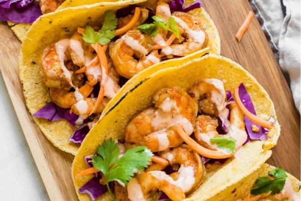 Shrimp tacos on a wooden cutting board.