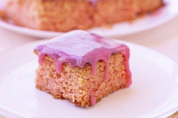 A piece of cake with pink icing on a plate, perfect for those looking for delicious brownie recipes.