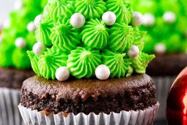 Cupcakes adorned with festive Christmas tree decorations made entirely of chocolate.