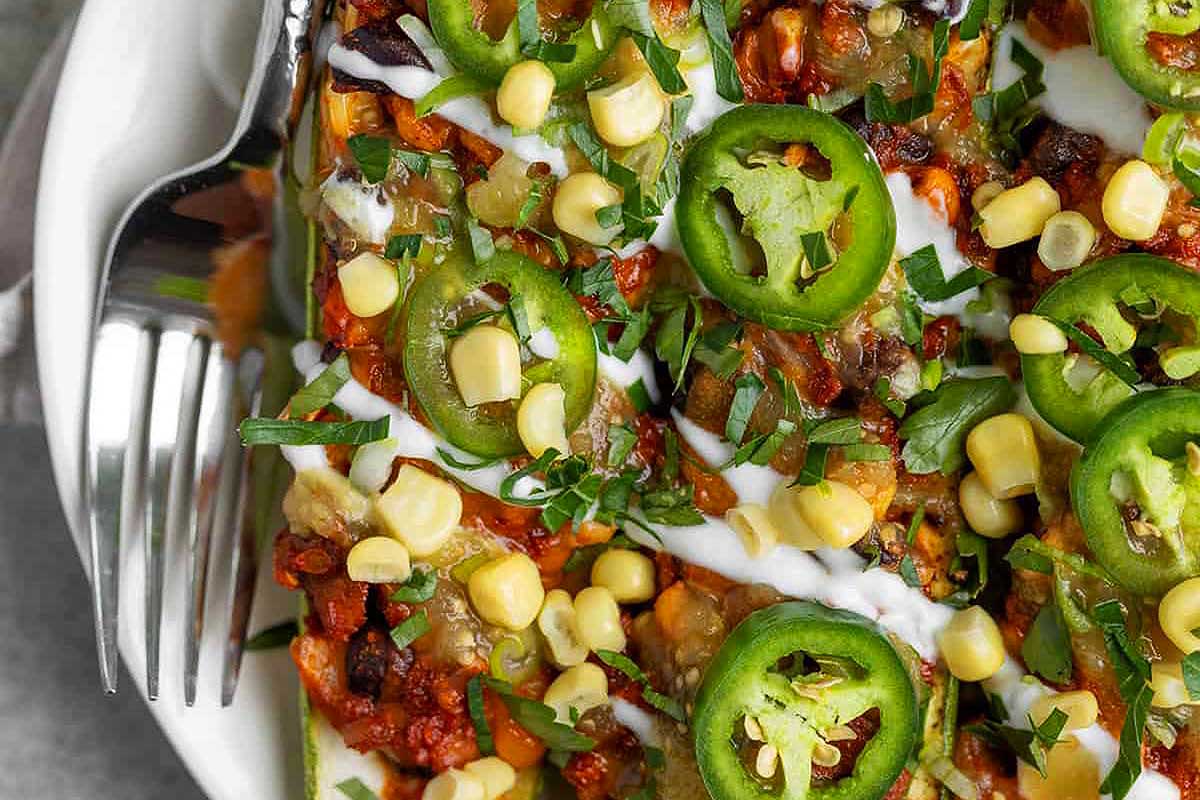 A plate of mexican enchiladas with corn and jalapenos.