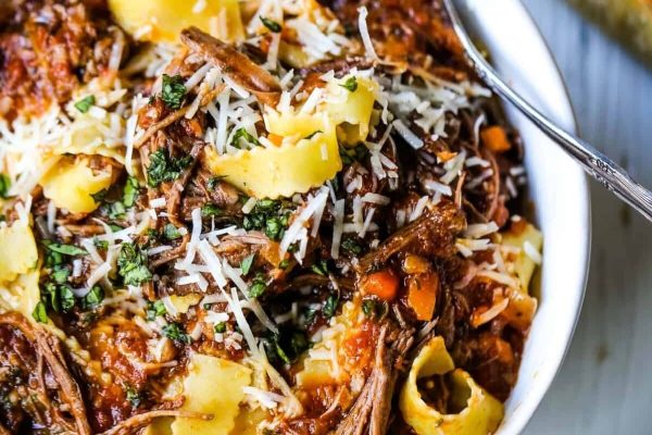 A white bowl filled with pasta and meat.