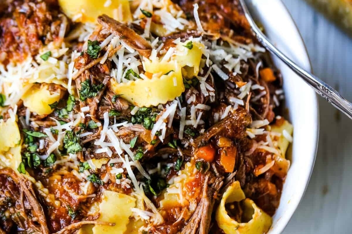 A white bowl filled with pasta and meat.