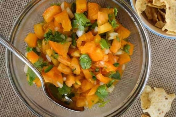 A bowl of salsa with tortilla chips, a spoon, and an Italian appetizer twist.