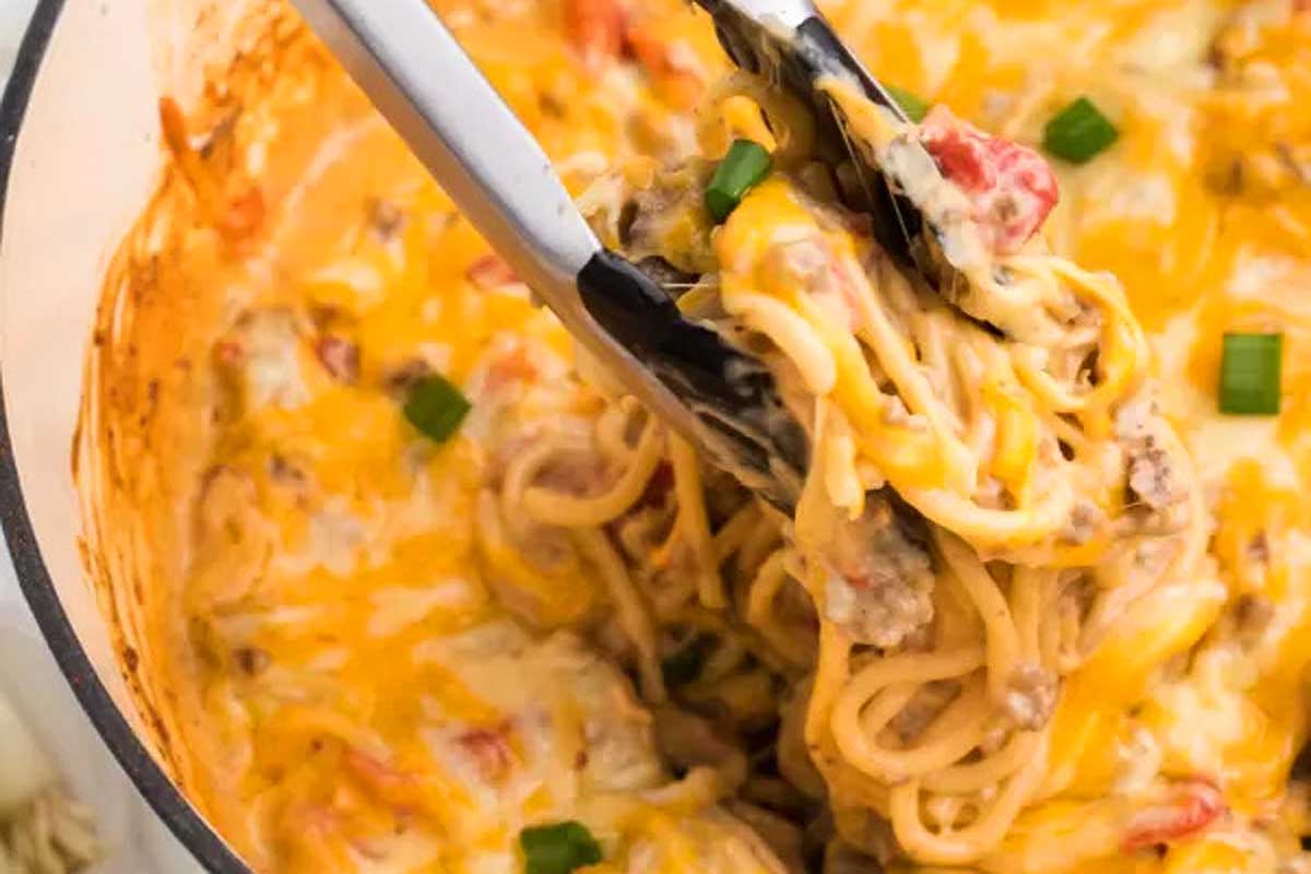 A spoon being lifted out of a pot of spaghetti and meatballs.