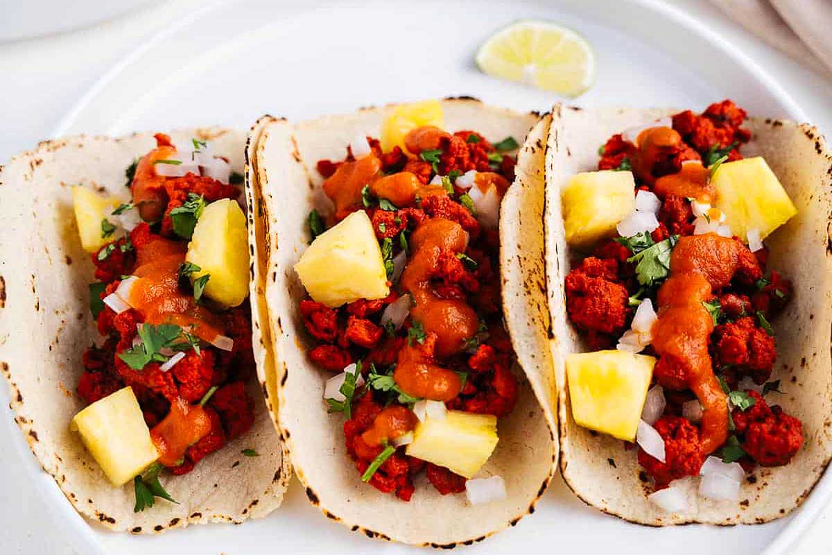 Three chicken tacos on a white plate.