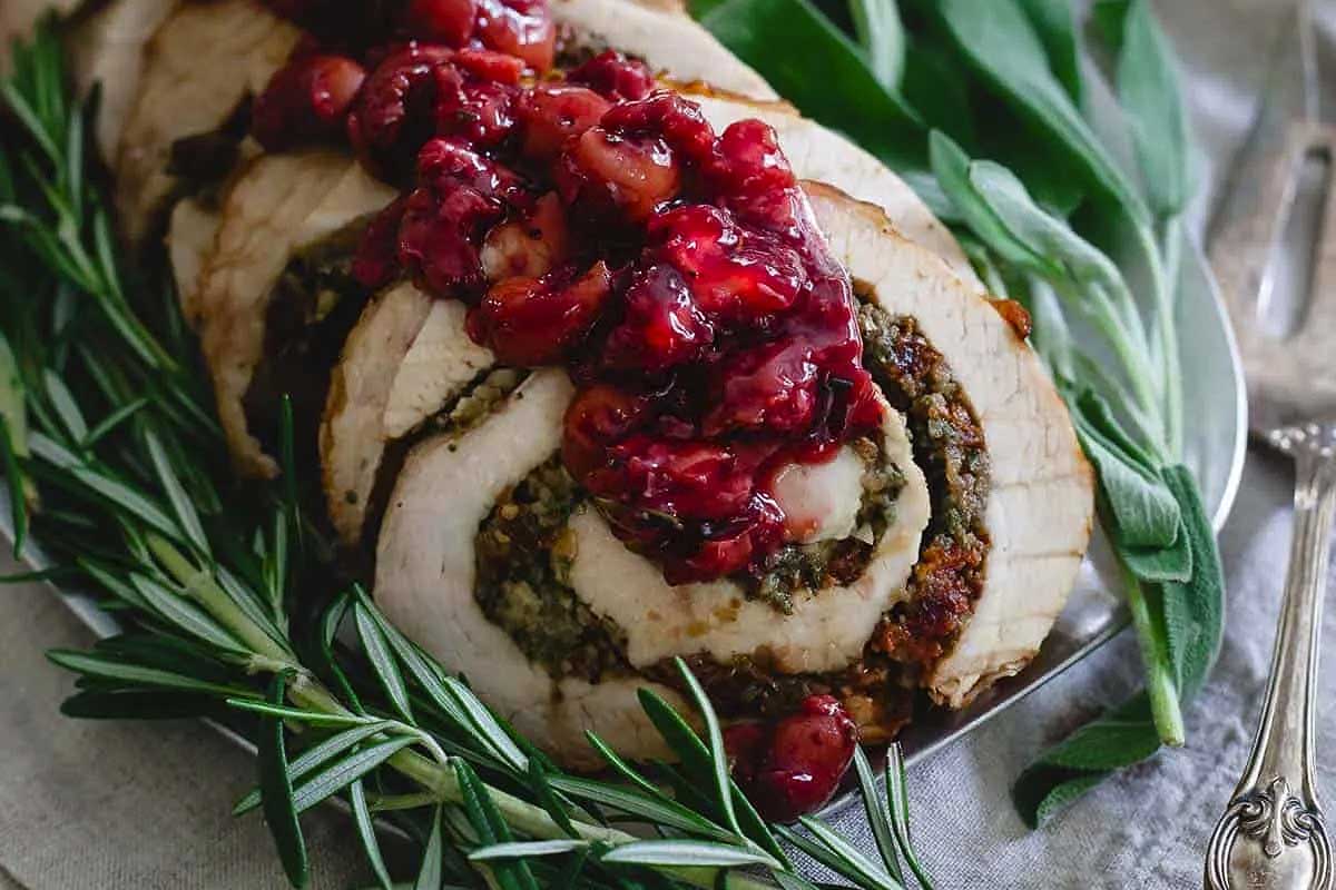 Friendsgiving feast featuring a succulent turkey stuffed with tangy cranberry sauce and garnished with fragrant sprigs of rosemary.