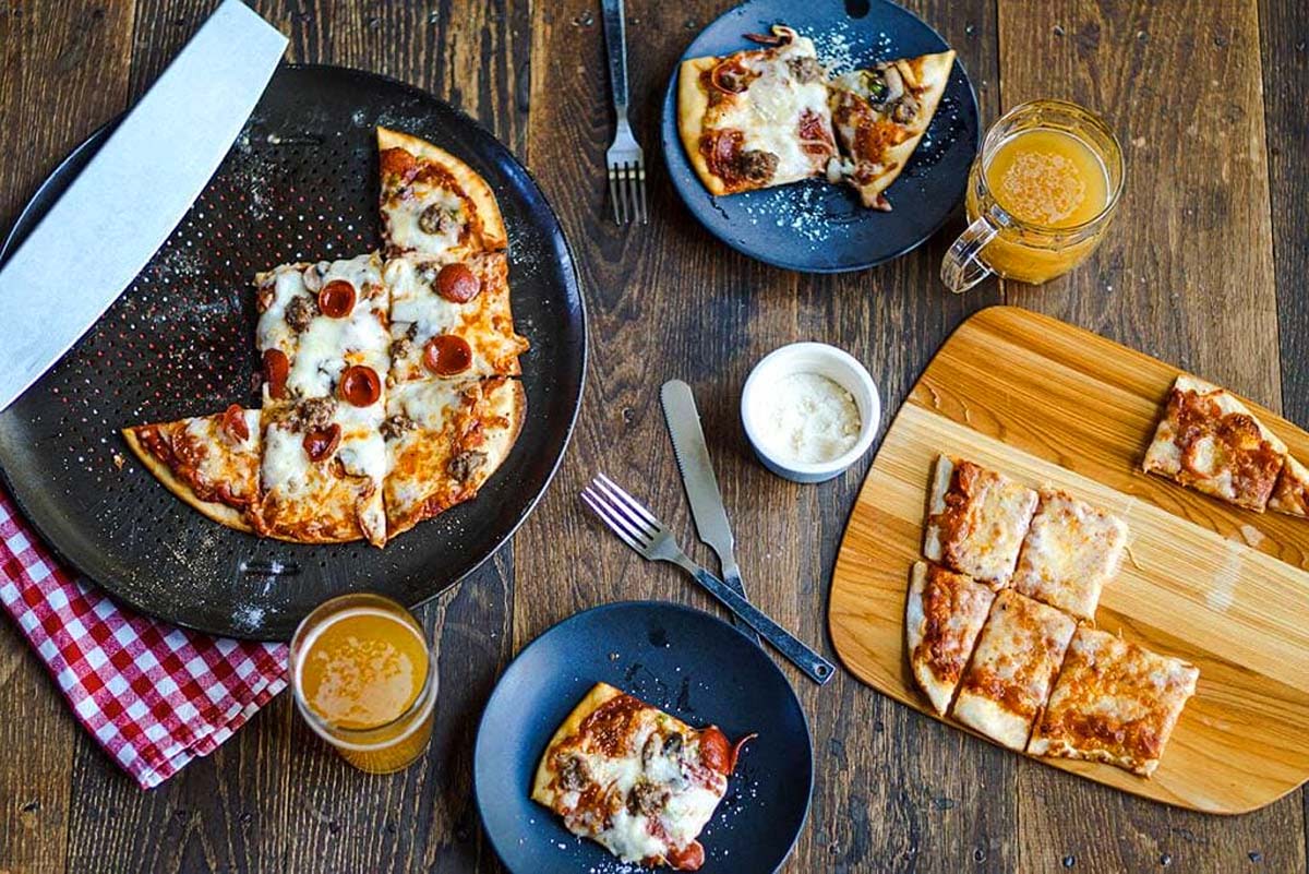 A pizza with pepperoni and cheese on a wooden table in a pub.