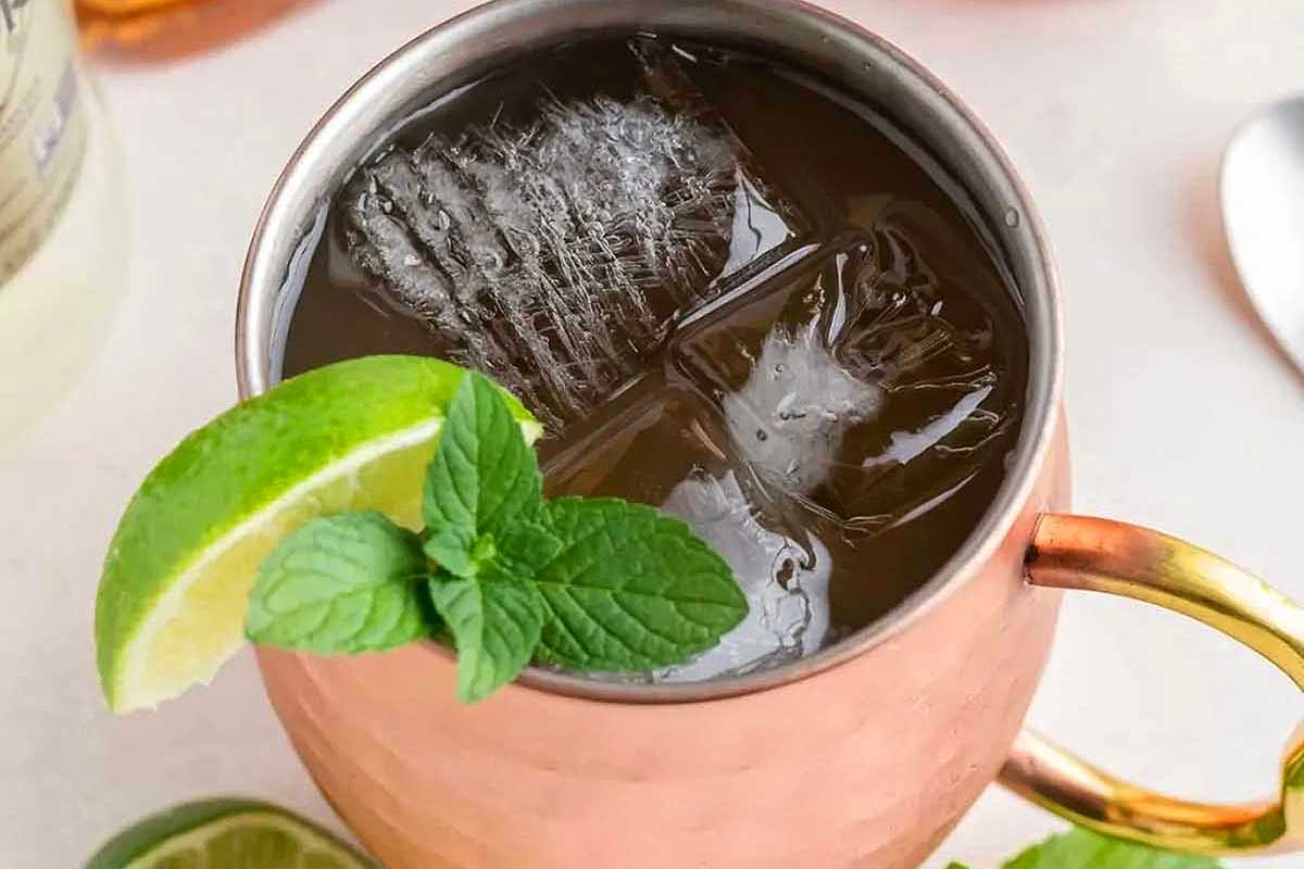 A refreshing Moscow mule with mint and ice served in a copper mug.