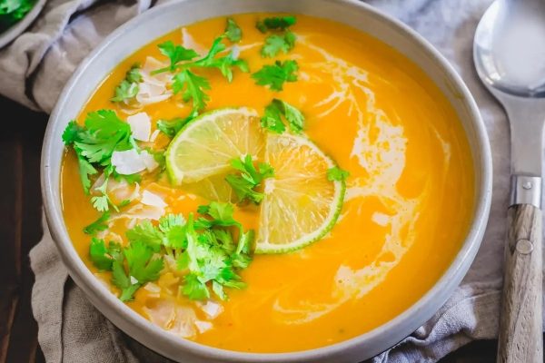 A bowl of cream soup with lime and cilantro.